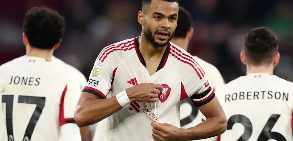 Jugador de Liverpool señalando su camiseta en el campo