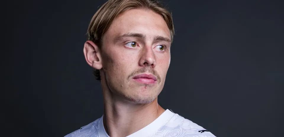 Jugador posando con camiseta blanca frente a fondo oscuro