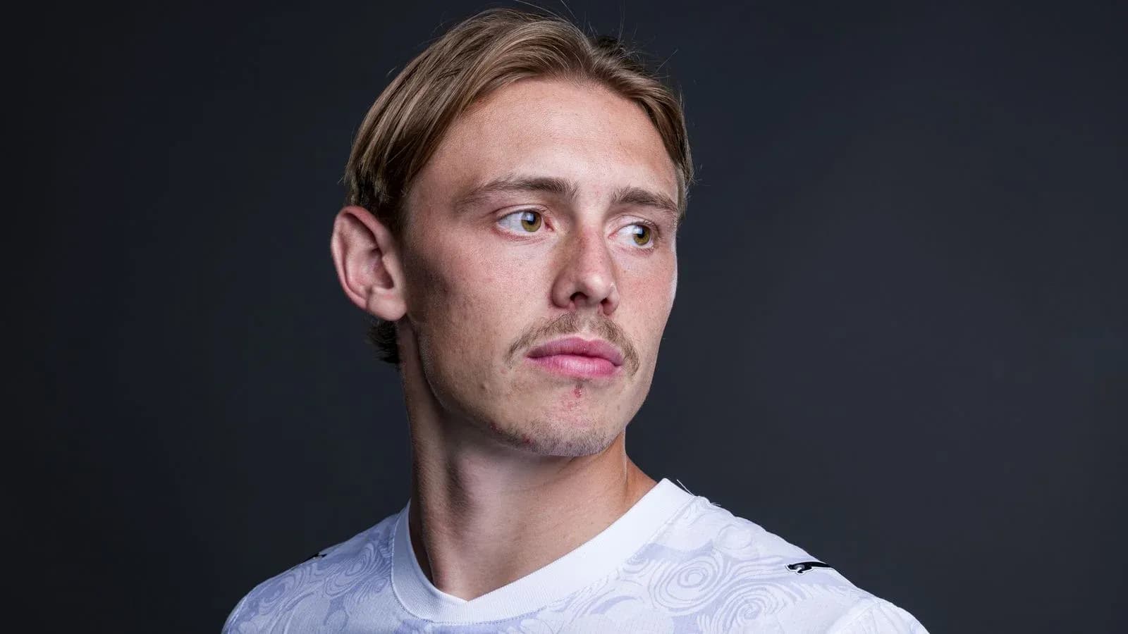Jugador posando con camiseta blanca frente a fondo oscuro