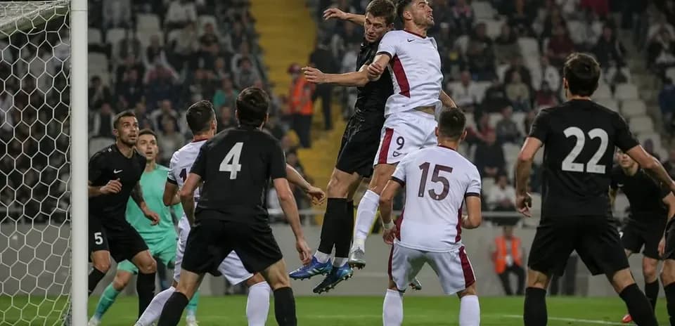 Jugadores saltando por el balón en el área de gol