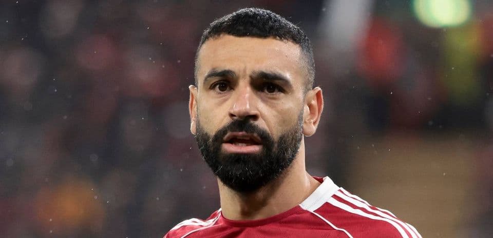 Jugador en primer plano con camiseta roja en estadio