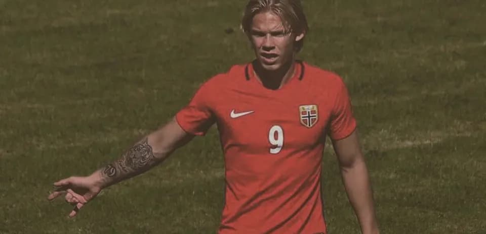 Jugador noruego en camiseta roja señalando durante partido