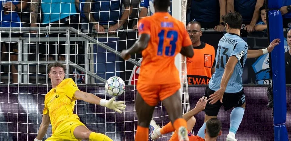 Jugador rematando mientras el portero intenta detenerlo