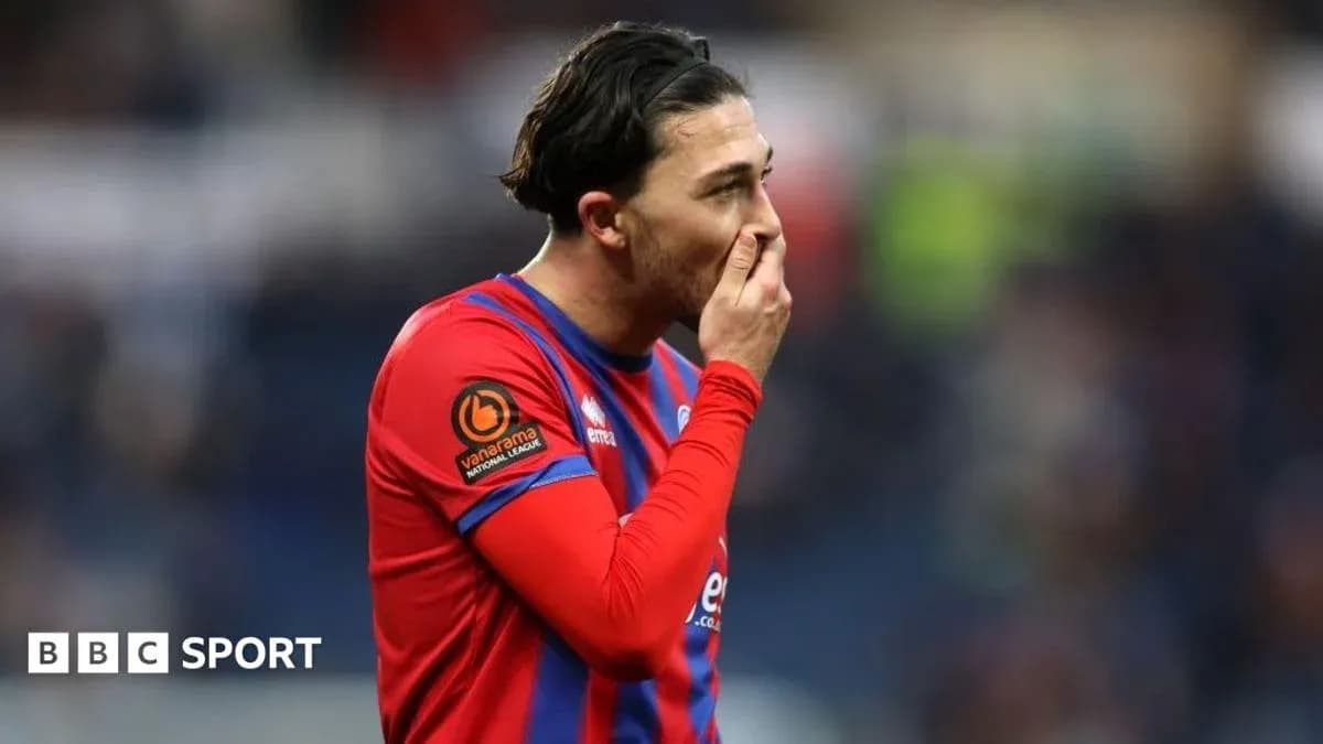 Jugador con camiseta roja tocándose la boca en el campo