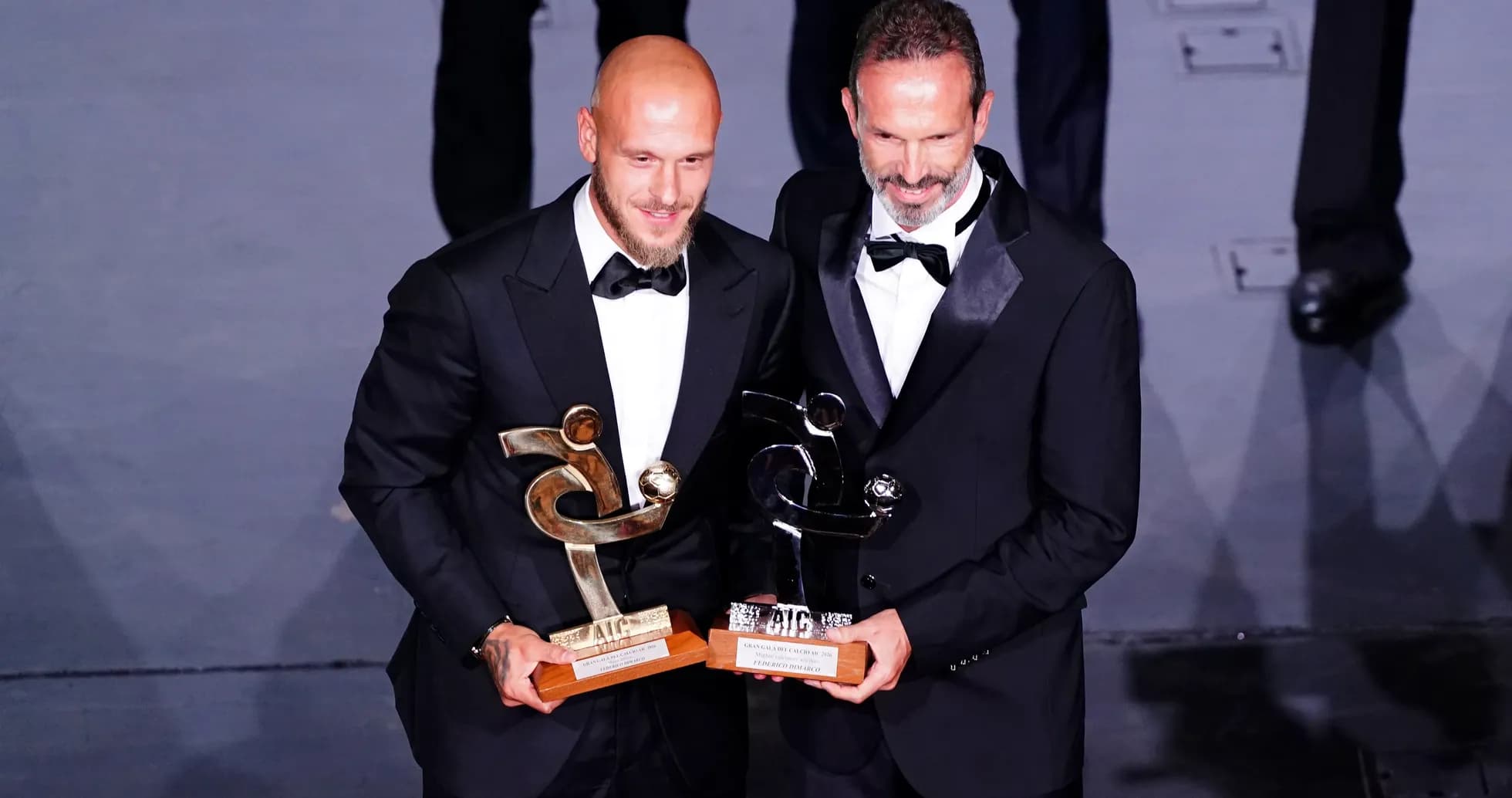 Dos hombres en trajes con premios en ceremonia