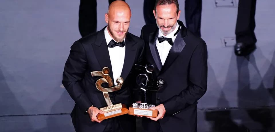 Dos hombres en trajes con premios en ceremonia