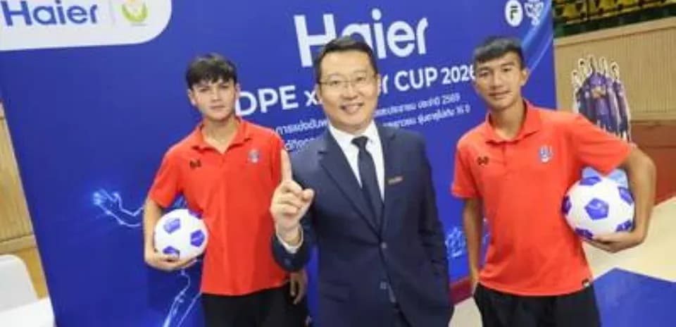 Tres personas posando con balones de fútbol en evento