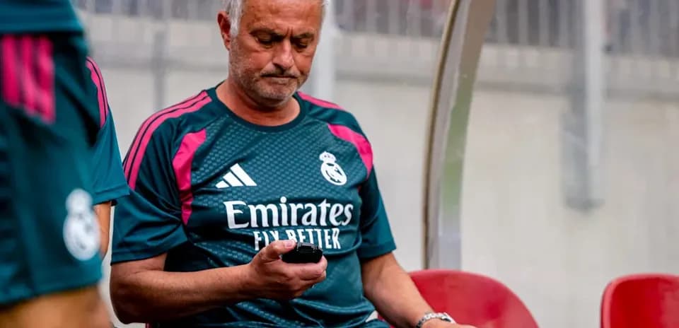 Entrenador sentado en el banquillo mirando su móvil