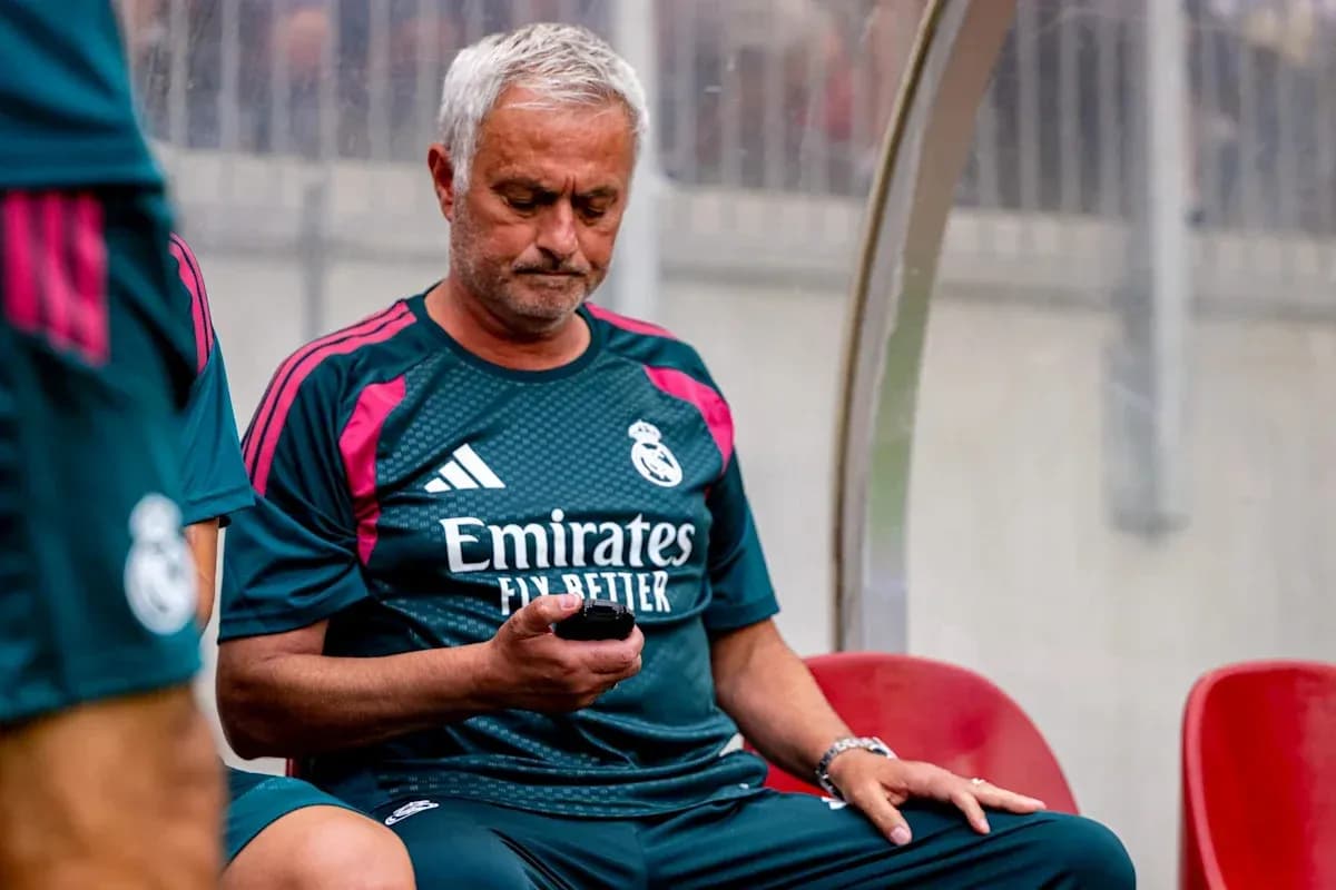 Entrenador sentado en el banquillo mirando su móvil