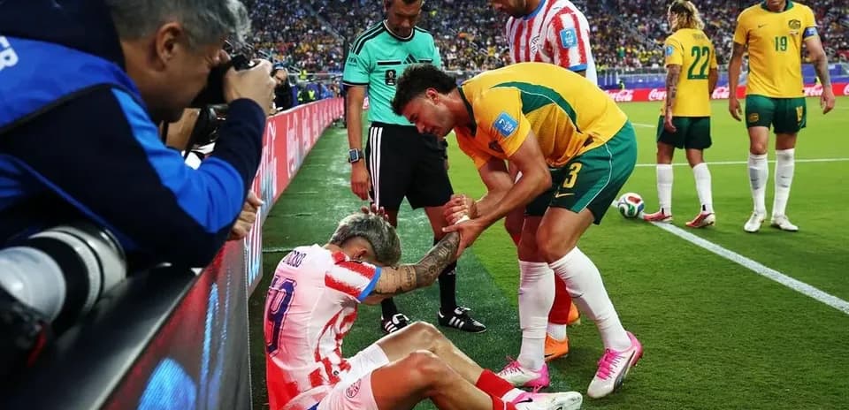Jugador caído siendo ayudado por adversarios en el campo