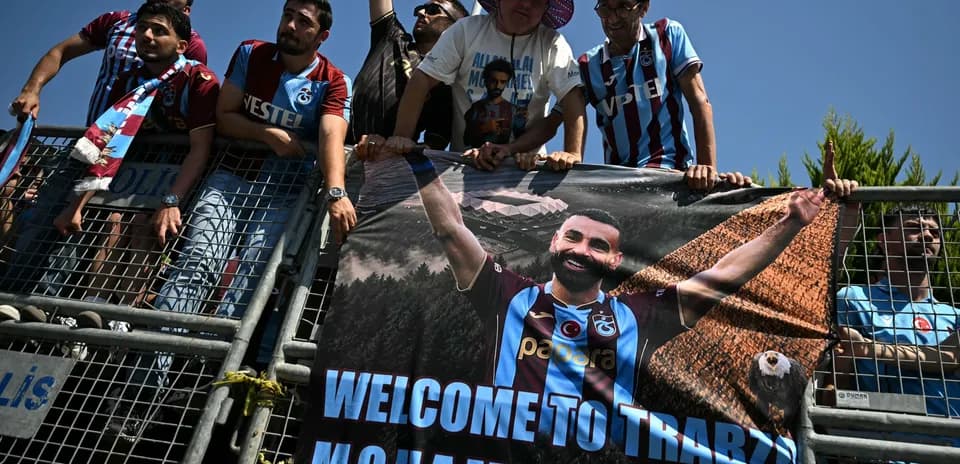Aficionados con pancarta dando la bienvenida a jugador