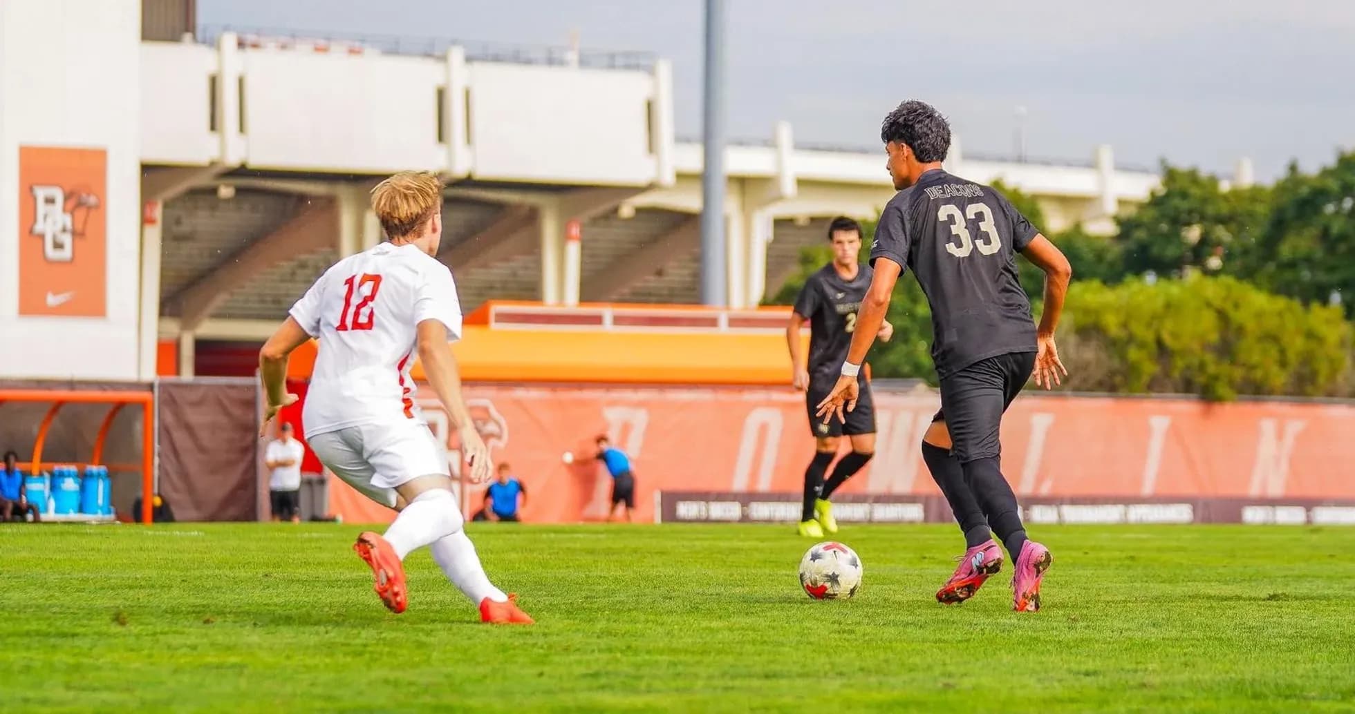Jugador con balón y rival en campo de fútbol
