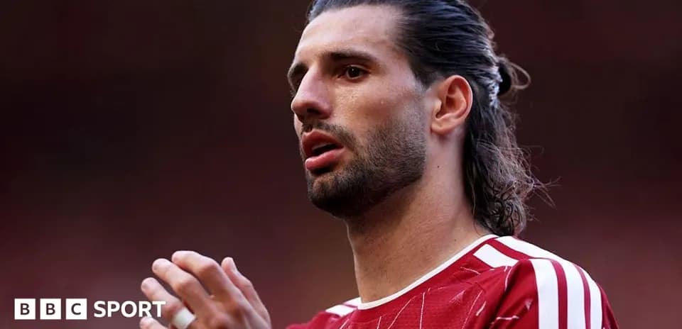 Jugador de fútbol en camiseta roja hablando en el campo