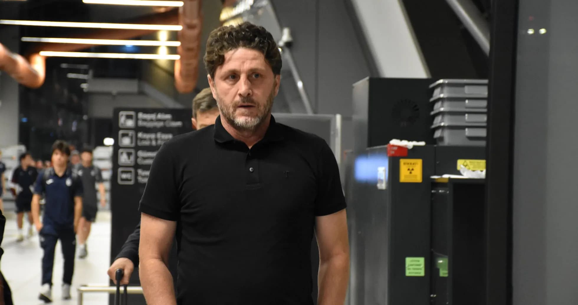 Entrenador caminando en el aeropuerto con equipo