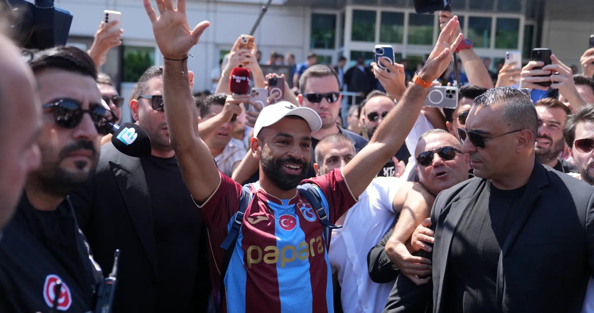 Jugador saludando a aficionados rodeado de seguridad