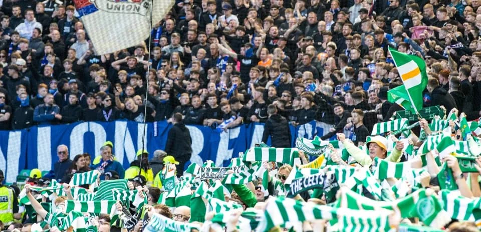 Aficionados con bufandas verdes animando en el estadio