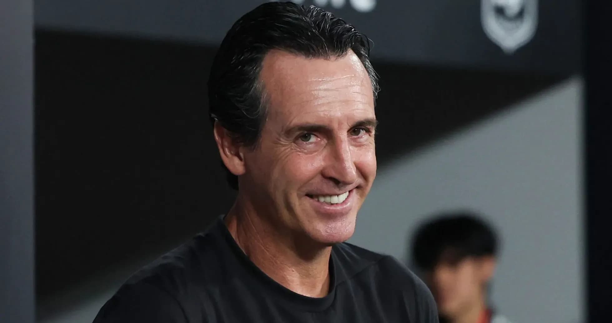 Entrenador sonriendo en la banca durante el partido
