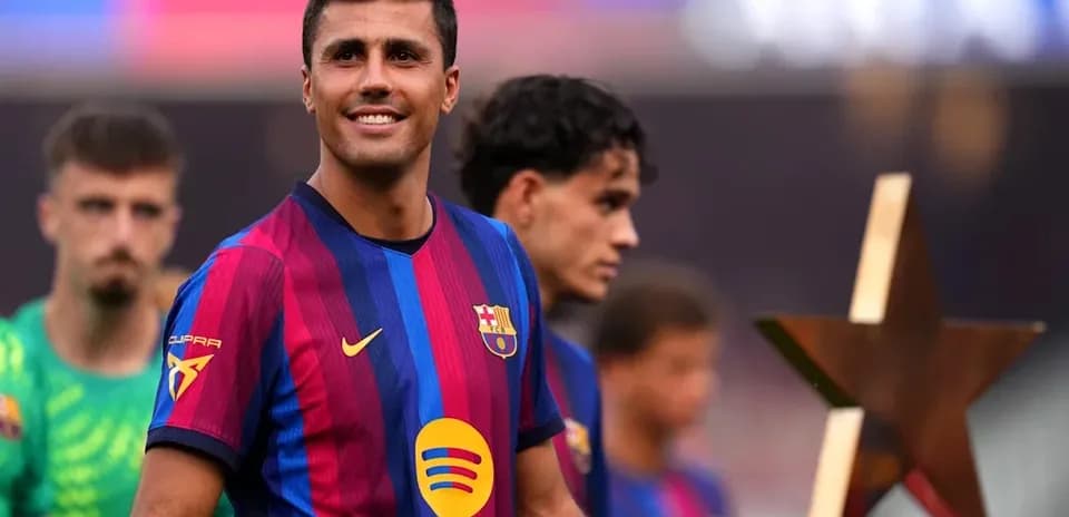 Jugador de Barcelona sonriendo junto a compañeros y trofeo