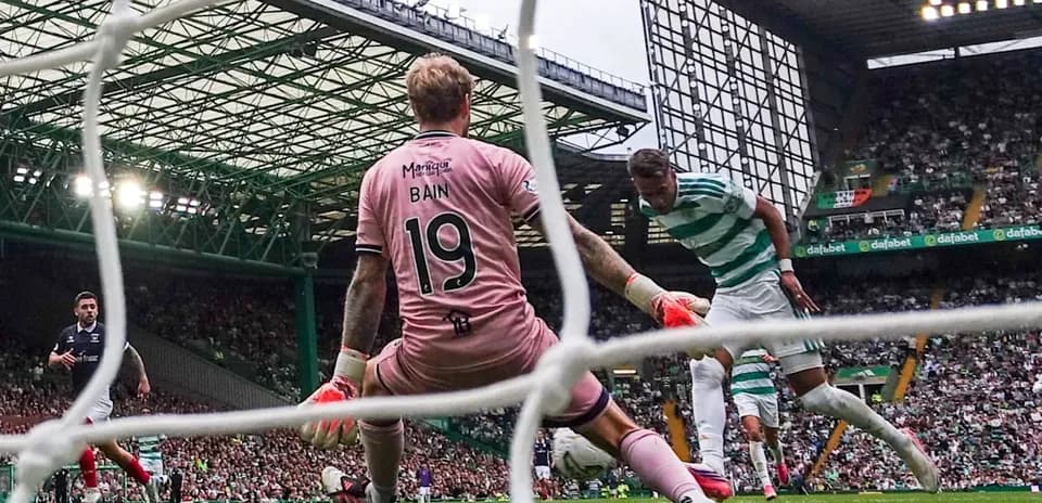 Jugador de Celtic disparando a portería con Bain defendiendo