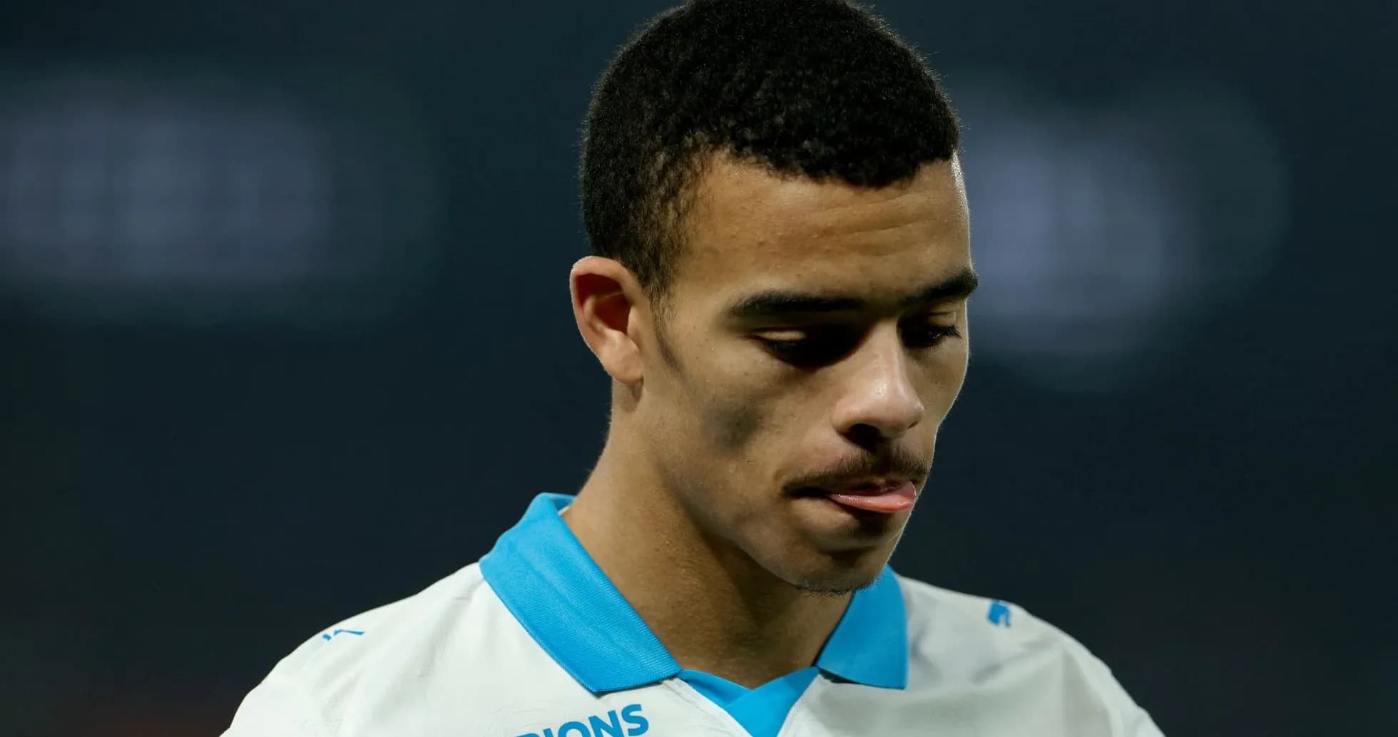 Jugador de fútbol en camiseta blanca mirando hacia abajo