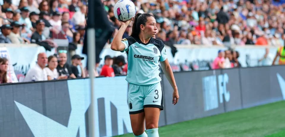 Jugadora lanzando el balón en partido de fútbol
