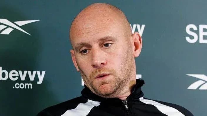 Entrenador en conferencia de prensa con expresión seria