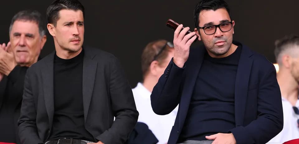 Dos hombres observando un evento deportivo desde la grada