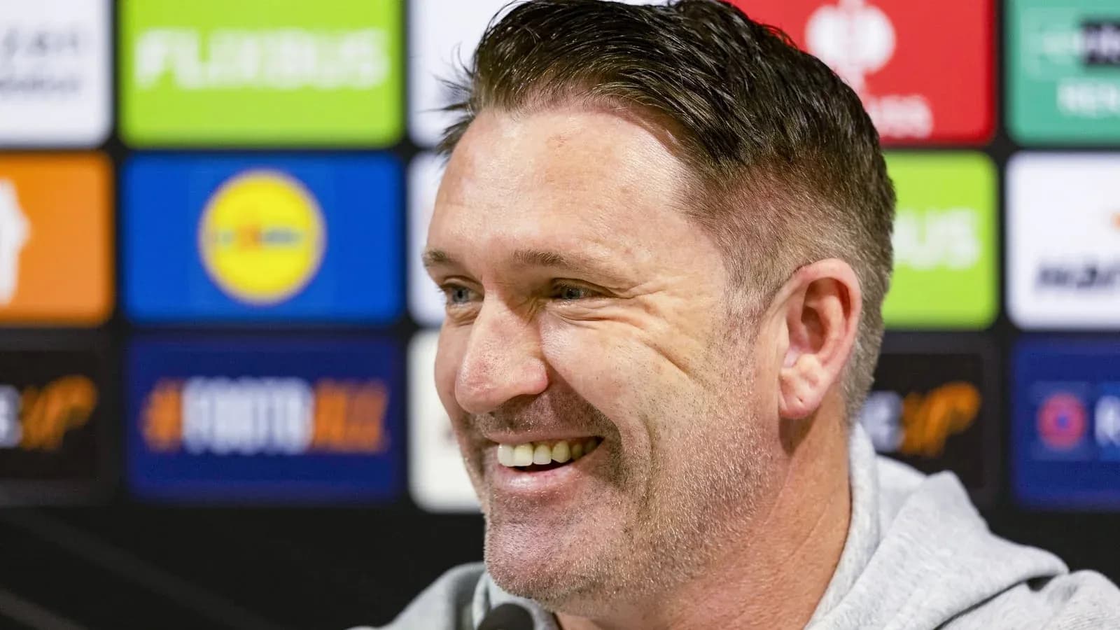 Entrenador sonriendo en rueda de prensa