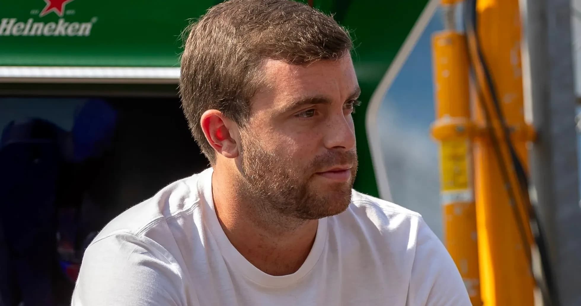 Hombre con camiseta blanca sentado cerca de un coche