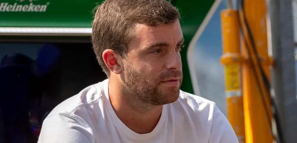 Hombre con camiseta blanca sentado cerca de un coche
