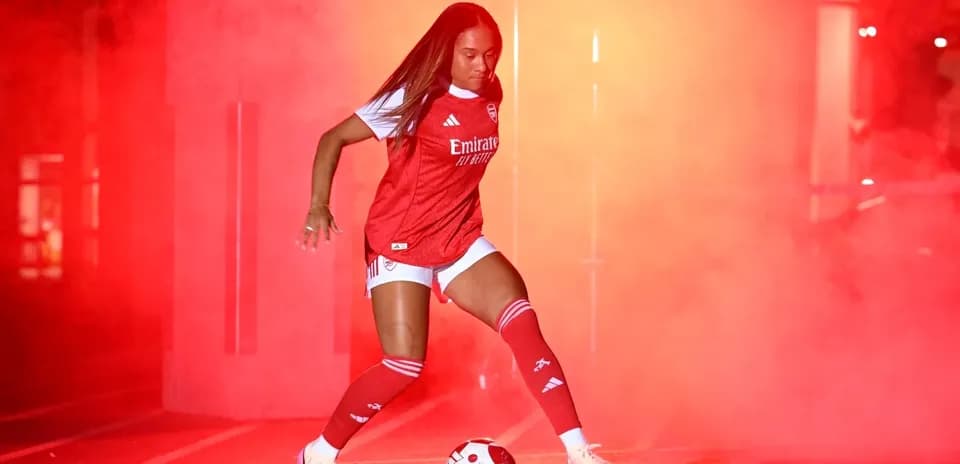 Jugadora de fútbol con balón en humo rojo