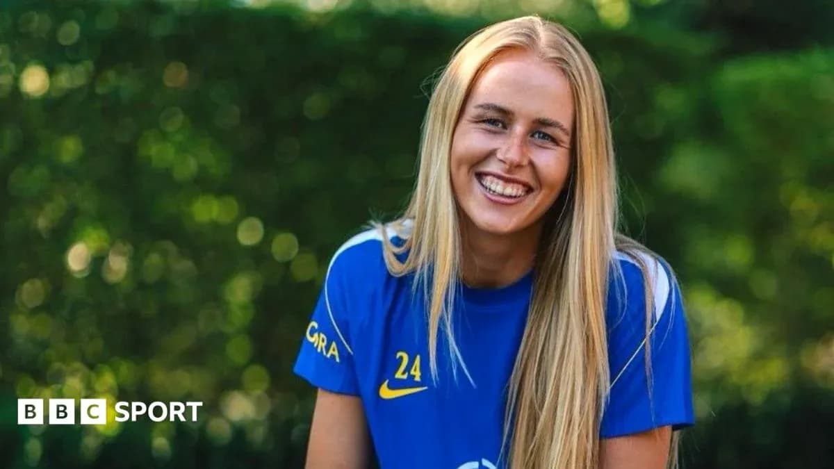 Jugadora sonriendo en uniforme azul de fútbol