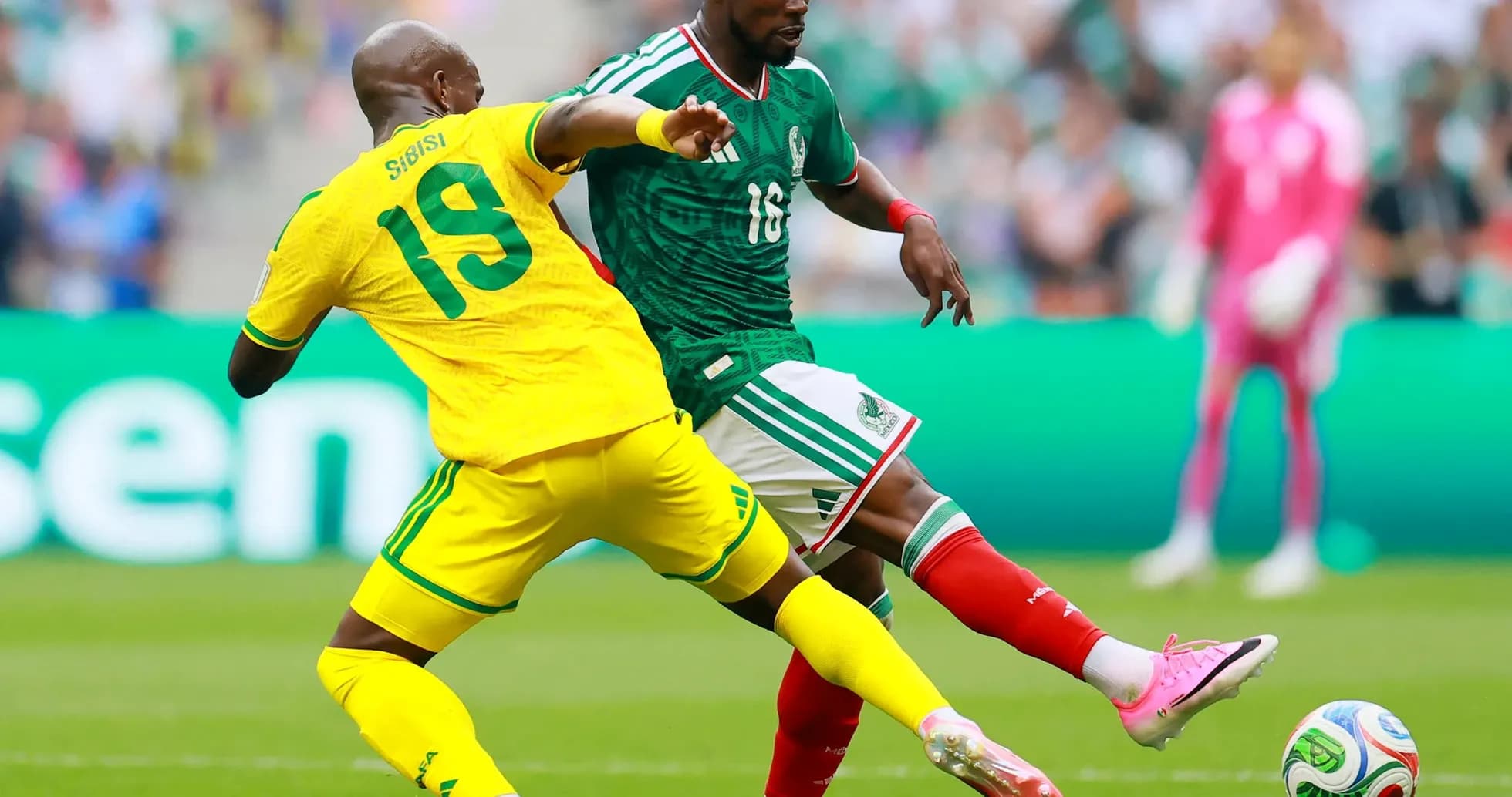 Jugador mexicano evadiendo a un defensor sudafricano