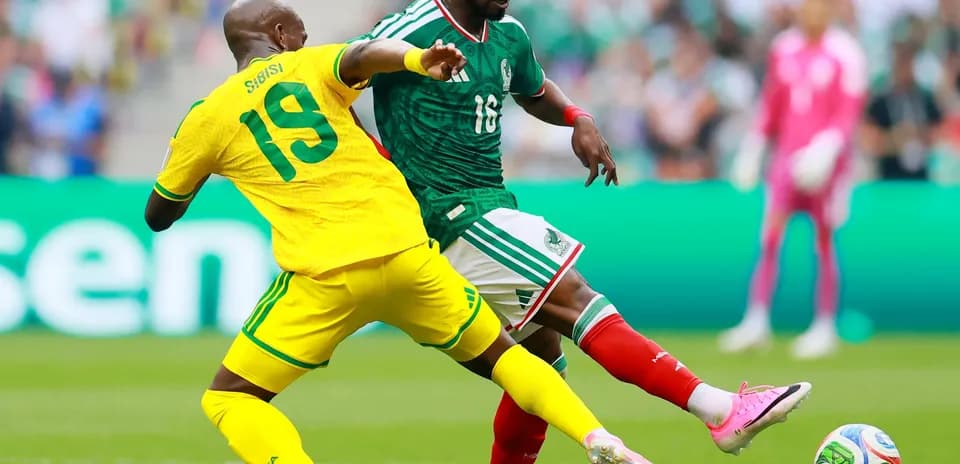 Jugador mexicano evadiendo a un defensor sudafricano