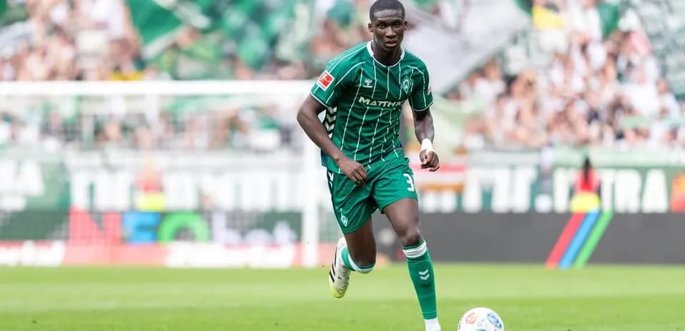 Jugador corriendo con balón en campo de fútbol