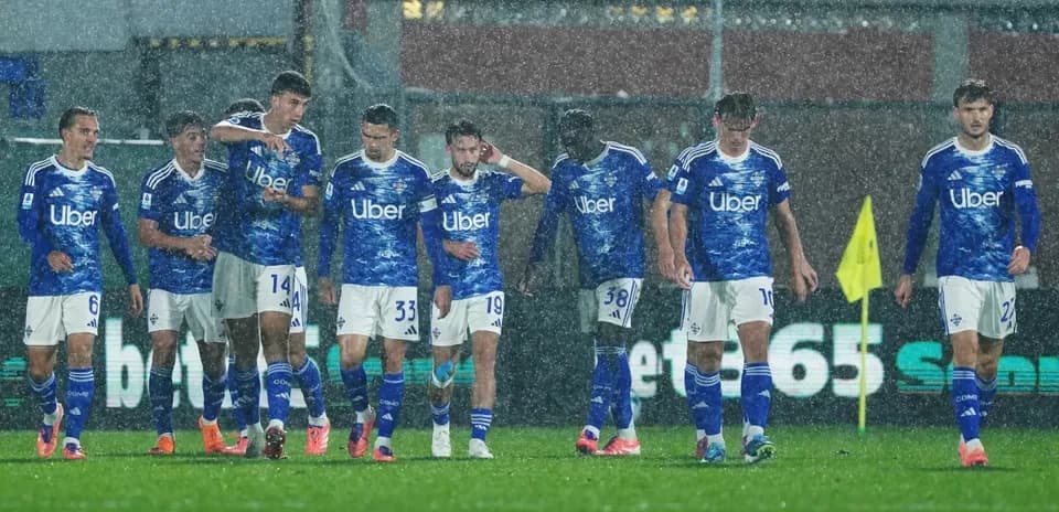 Jugadores de Como en partido de fútbol bajo la lluvia