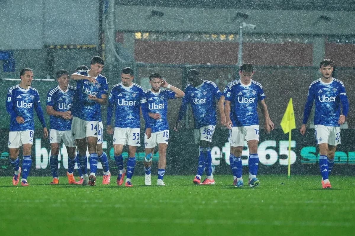 Jugadores de Como en partido de fútbol bajo la lluvia