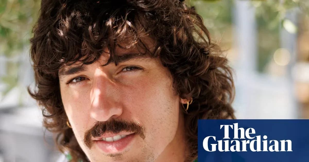 Hombre con cabello rizado y bigote, sonriendo