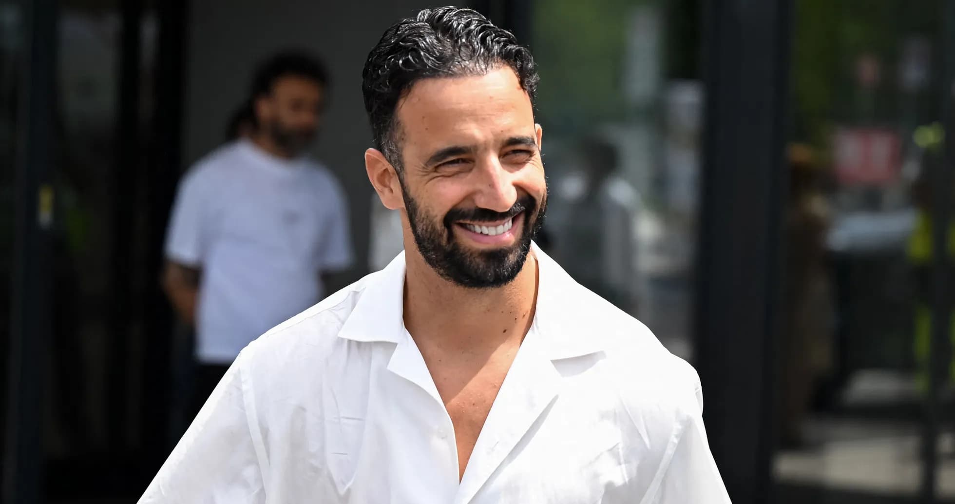 Hombre sonriendo con camisa blanca en exterior