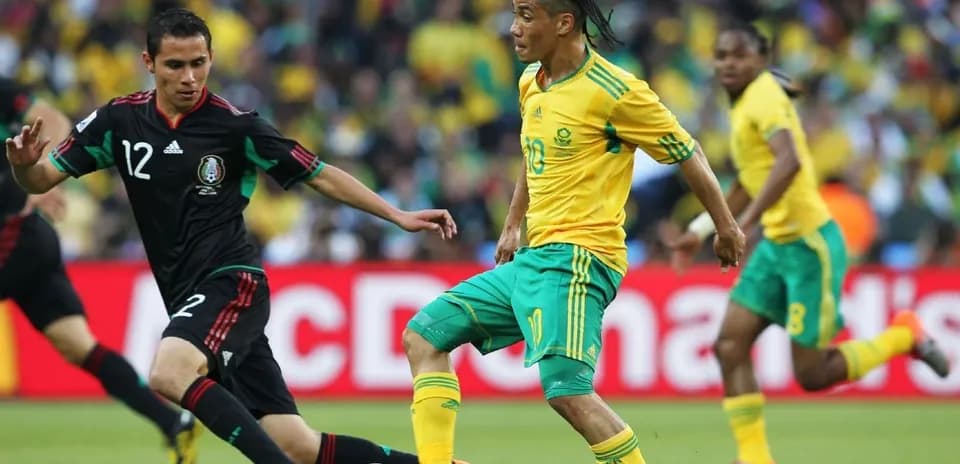Jugadores de México y Sudáfrica compitiendo por el balón