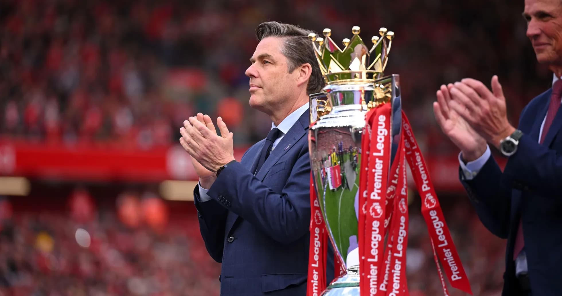 Persona aplaudiendo junto a trofeo de Premier League