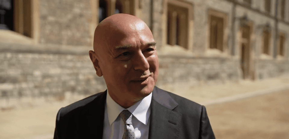 Hombre con traje sonriendo frente a edificio histórico