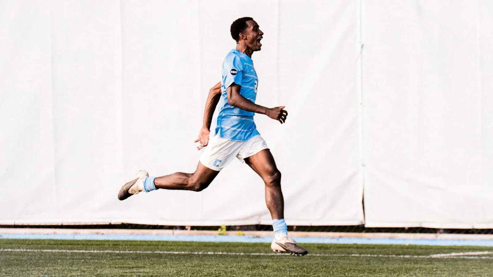 Jugador corriendo en campo con camiseta celeste Jugador corriendo en campo con camiseta celeste
