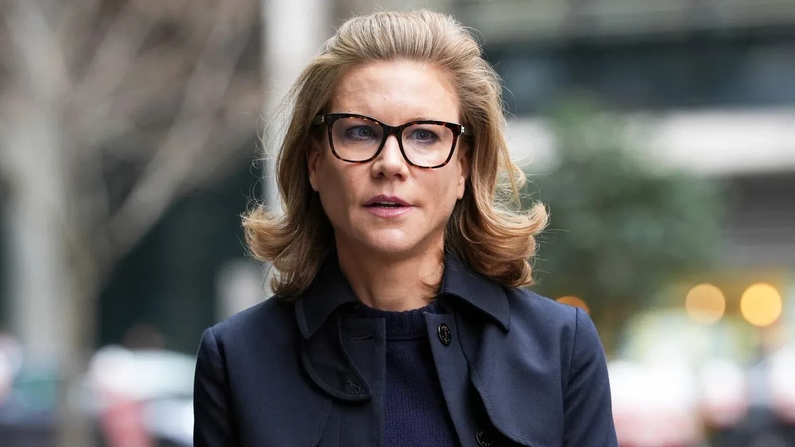 Mujer con gafas y abrigo caminando por la calle Mujer con gafas y abrigo caminando por la calle
