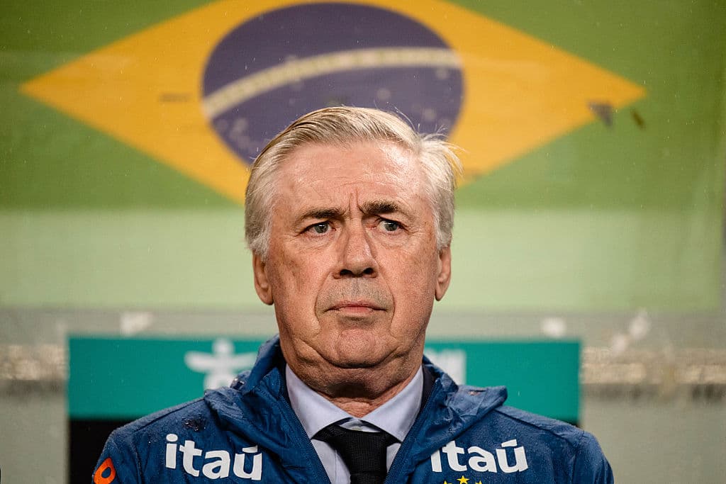 Entrenador con chaqueta itau frente a bandera brasileña Entrenador con chaqueta itau frente a bandera brasileña