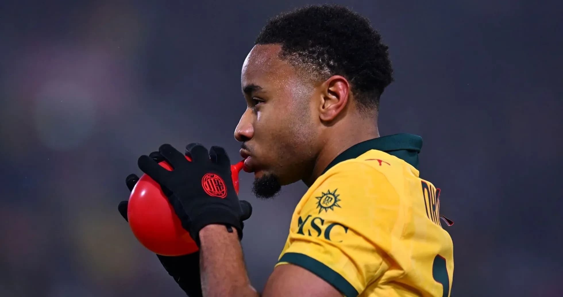 Jugador soplando un globo rojo durante el partido Jugador soplando un globo rojo durante el partido