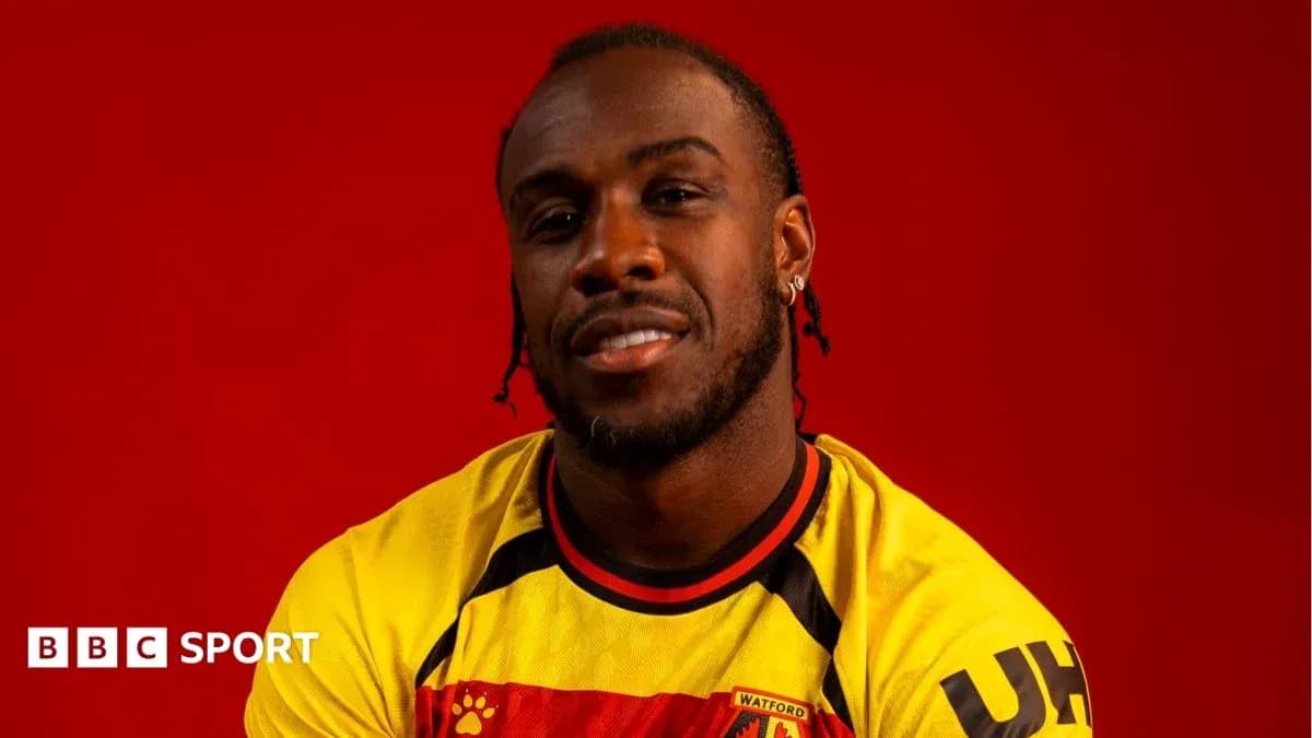 Jugador posando con camiseta de Watford frente fondo rojo Jugador posando con camiseta de Watford frente fondo rojo