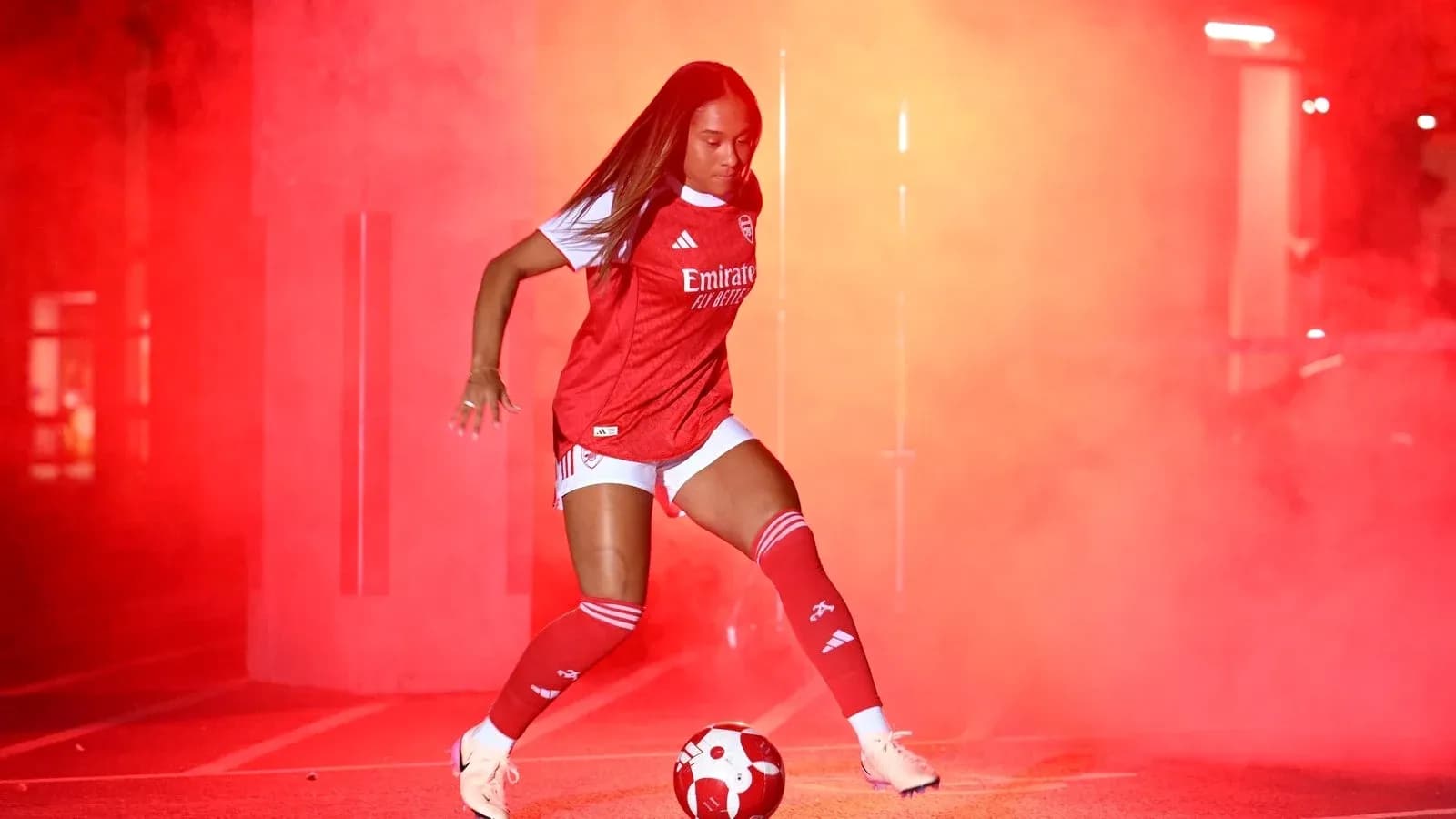 Jugadora de fútbol con balón en humo rojo Jugadora de fútbol con balón en humo rojo