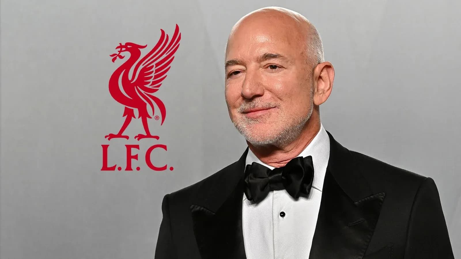 Hombre con traje y pajarita junto al logo de Liverpool Hombre con traje y pajarita junto al logo de Liverpool