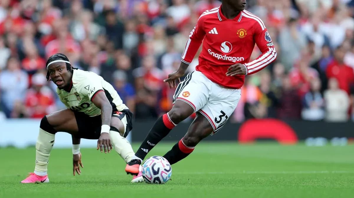 Jugador de Manchester United driblando mientras rival cae Jugador de Manchester United driblando mientras rival cae